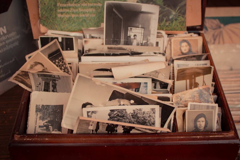 A collection of old black-and-white photographs stored in a vintage wooden box, evoking nostalgia.