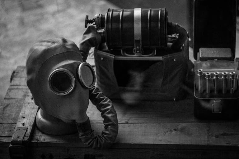 Black and white photo of a vintage gas mask and equipment on a wooden box.