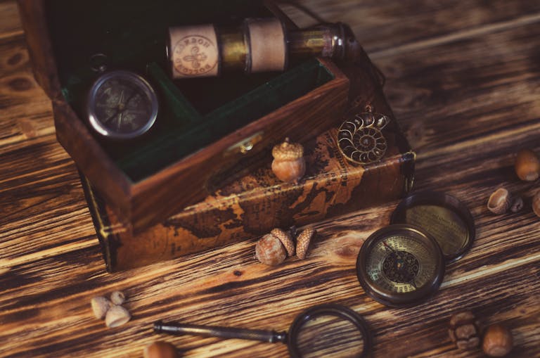 Intriguing flat lay of vintage compasses and a treasure box on a rustic wooden table.