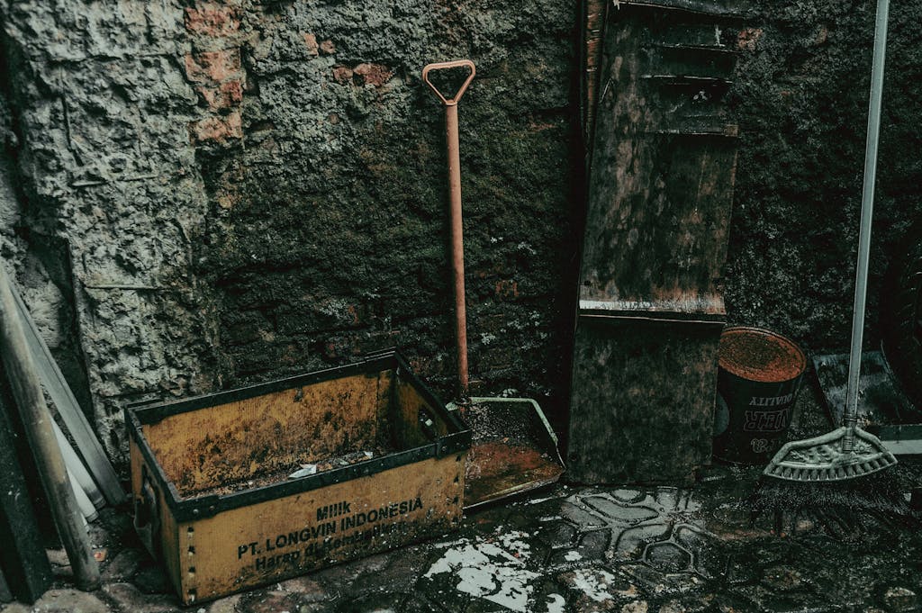 Old gardening tools against an aged stone wall with text and weathered textures.