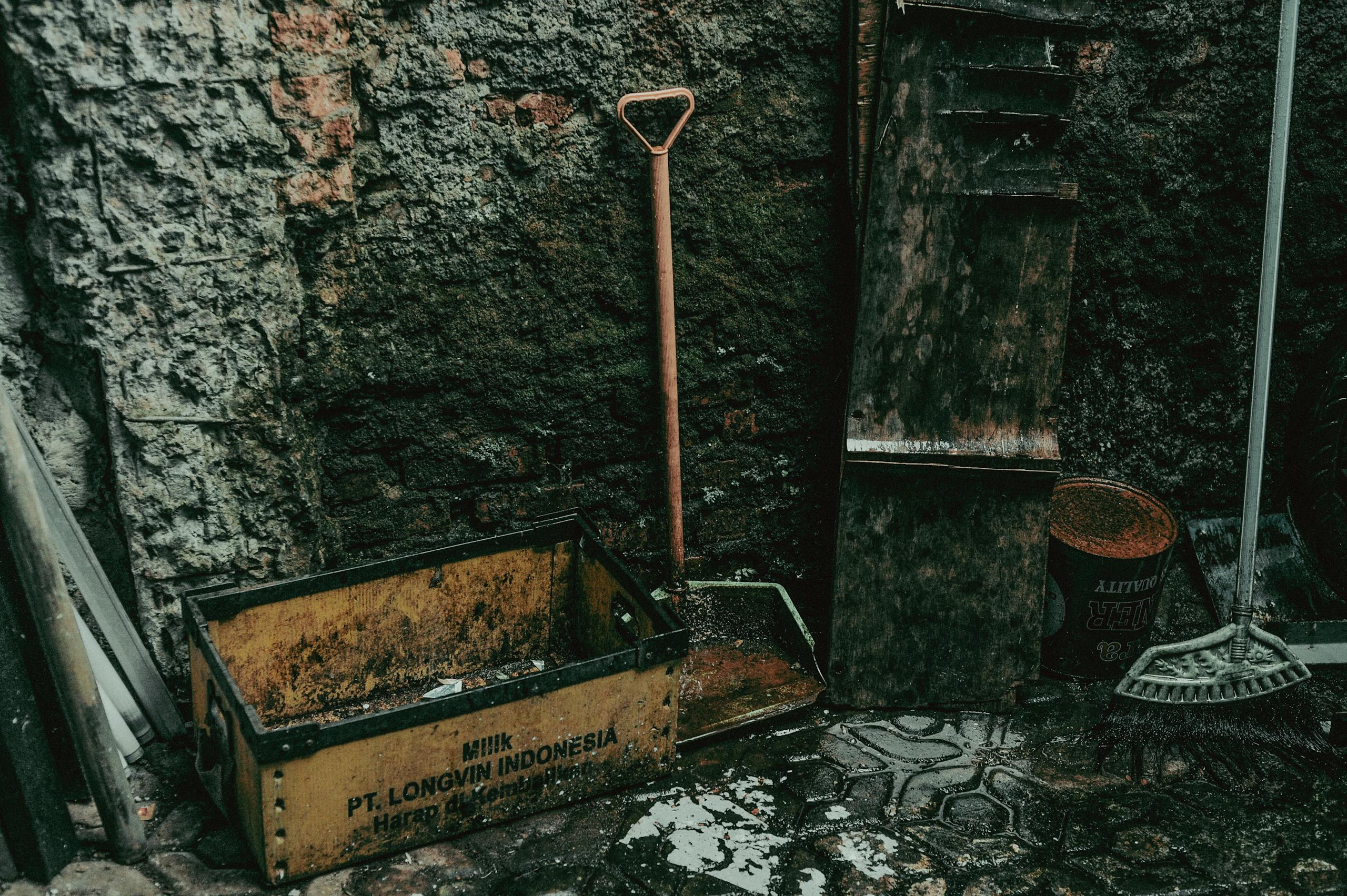 Old gardening tools against an aged stone wall with text and weathered textures.