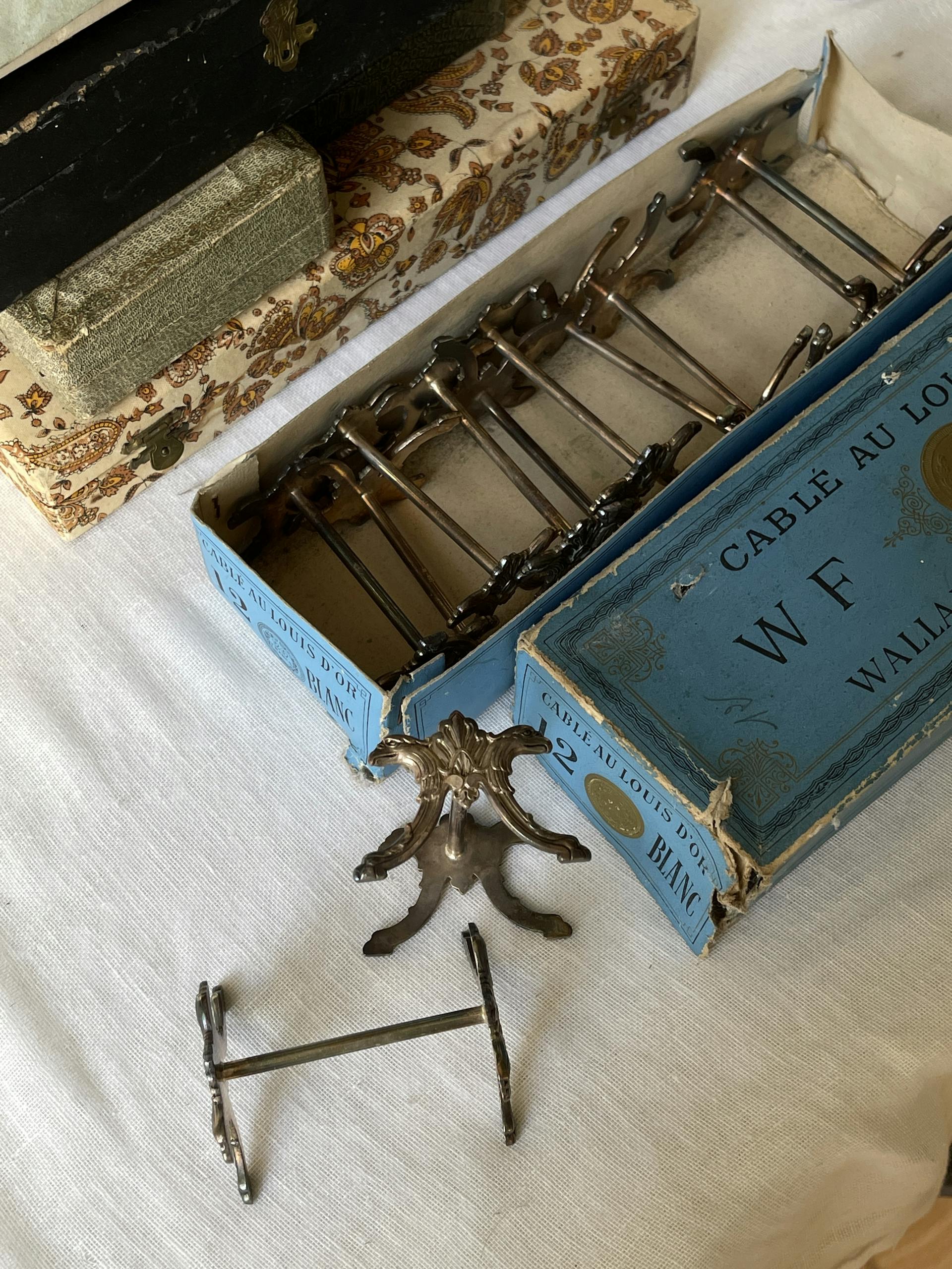 Old metal doorknobs displayed in vintage, decorative boxes on a table.